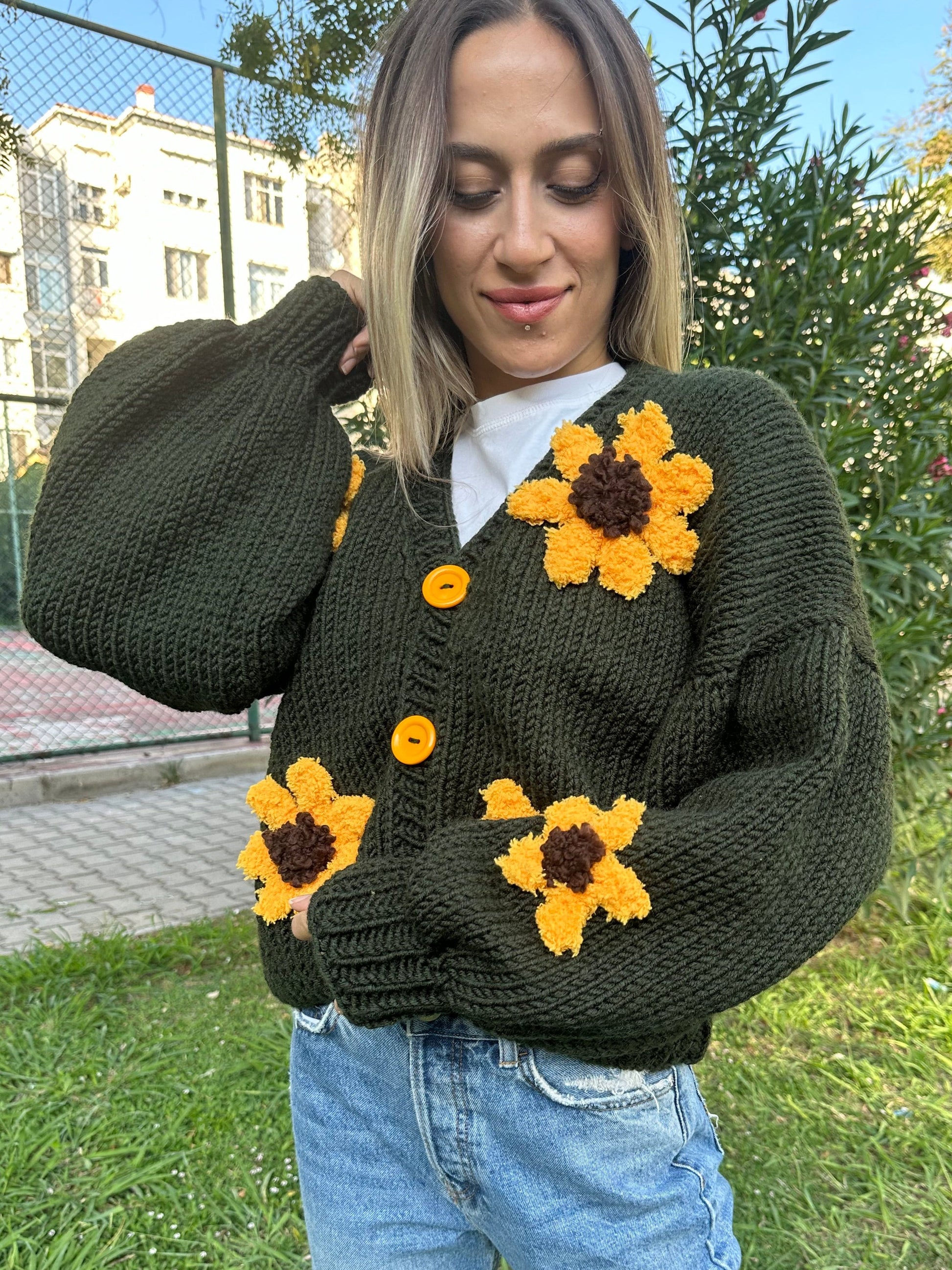 military green cardigan, sunflower knit cardigan, cozy green sweater, hand-knitted sunflowers, relaxed fit cardigan, soft yarn sweater, casual knitwear, earthy tone cardigan, unique floral design, stylish layering piece