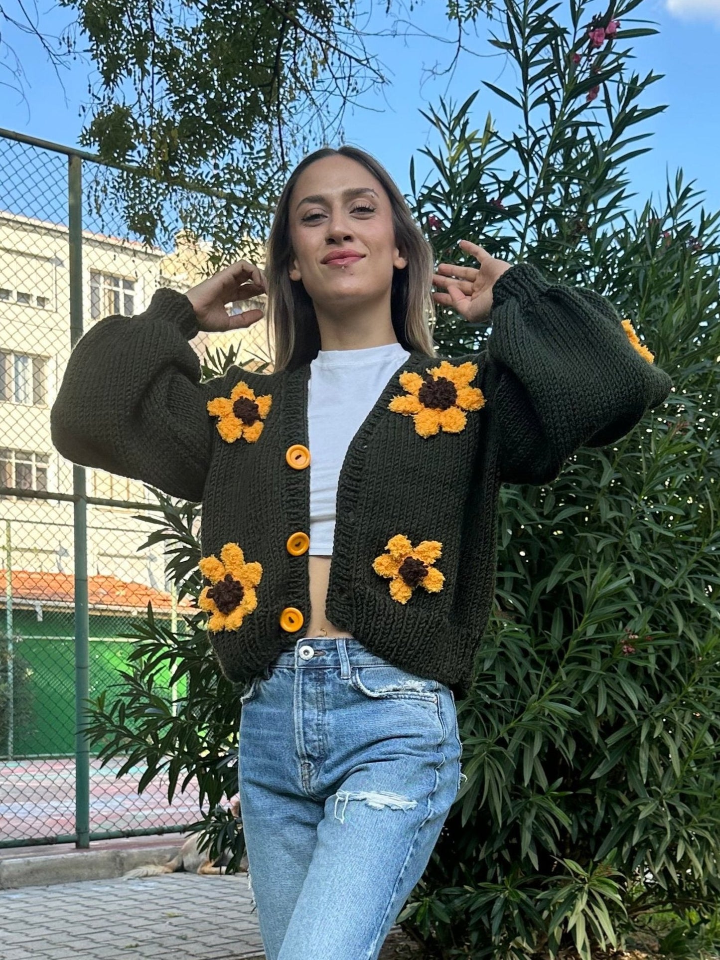 military green cardigan, sunflower knit cardigan, cozy green sweater, hand-knitted sunflowers, relaxed fit cardigan, soft yarn sweater, casual knitwear, earthy tone cardigan, unique floral design, stylish layering piece